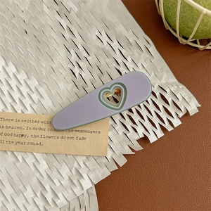 Detail view of a matte purple heart-shaped hair claw clip with dark green edges and gold clip