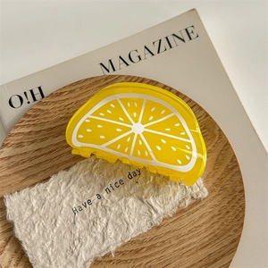 Détail d'une pince à cheveux en acrylique en forme de citron jaune sur fond vintage