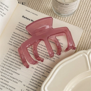 Détail d'une pince à cheveux violette translucide posée sur une page de livre