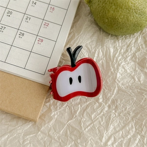 Close-up of cute red apple hair claw clip made of acetate on a desk setup