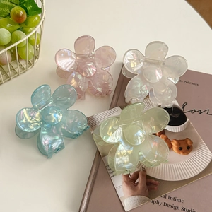 Pinces à cheveux fleurs élégantes aux couleurs nacrées irisées sur une scène de bureau blanc