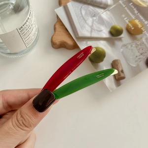 Elegant leaf-shaped acetate hair clips in red and green with gold lettering detail