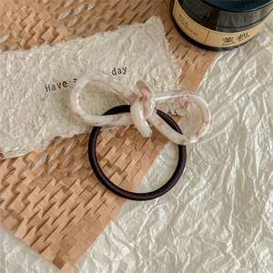 Detail of high-elasticity hair tie with marble-textured resin bow on decorative surface