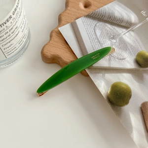 Olive green acetate hair clip with gold Creation France logo on elegant wooden tray