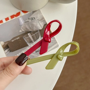 Barrettes à cheveux élégantes en acétate avec nœuds rouge et olive présentées à la main