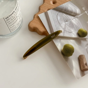Detailed view of an olive green acetate willow leaf hair clip with Creation France logo