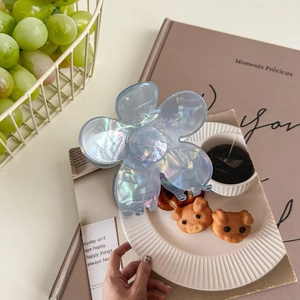 Détail d'une grande pince à cheveux fleur bleu clair irisé sur un livre vintage