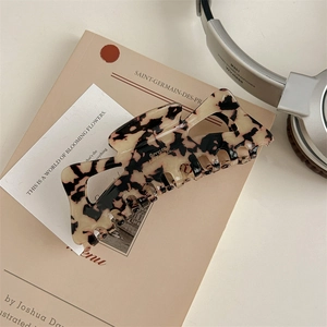 Detail of 13cm oversized tortoiseshell hair claw clip resting on a vintage book