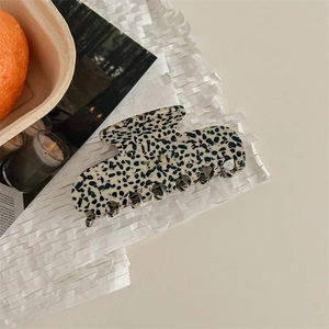 Vue détaillée d'une pince à cheveux en acétate motif dalmatien avec lettrage doré