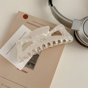 Detail showing the 13cm pearl white hair claw clip with geometric hollow and elegant brand text