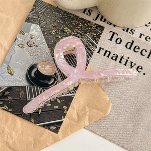 Close-up of pink acetate hair claw clip with pearlescent finish and gold metal spring