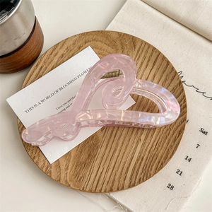 Détail d'une grande pince à cheveux rose en forme de cœur avec texture perlée élégante