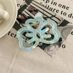 Detail of light blue pearlescent bow hair claw clip showing golden metal spring