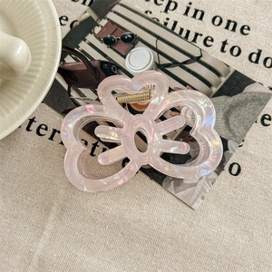 Detail of pearlescent pink butterfly hair claw clip with golden metal spring