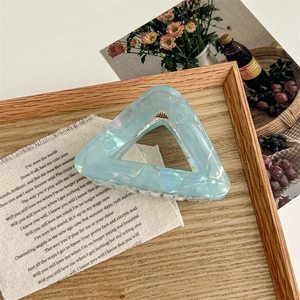 Détail d'une pince à cheveux triangulaire bleu clair en acétate avec reflets nacrés