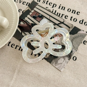 Detail of a large pearlescent white acrylic claw clip with an elegant hollow clover design