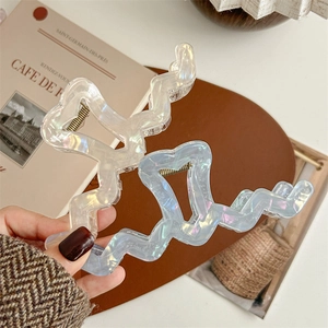 Large iridescent wave-shaped hair claws in elegant gold and blue aurora finishes
