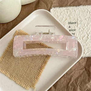 Details einer extra großen perlmuttrosa Acetat-Haarklammer mit Muscheltextur und Goldfeder