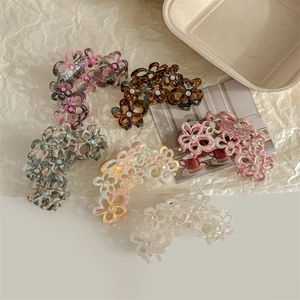 Vista dall'alto di fermagli per capelli a fiore in acetato con strass su carta beige