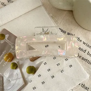 Detail of a large pearlescent acrylic hair claw clip with a chic marble finish texture