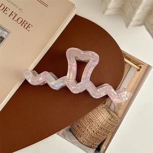 Detailed view of iridescent heart-shaped hair claw clip with wavy edges in French style