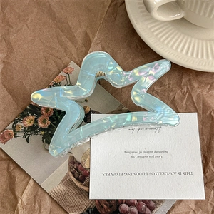 Detail of hollow star hair claw clip with colorful iridescent finish on vintage paper