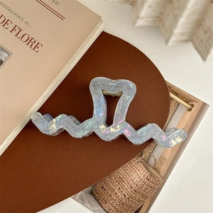 Close-up of light blue pearlescent oversized wave hair claw with heart design