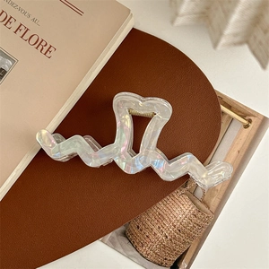 Close-up of heart-shaped iridescent pearl hair claw clip with wave design on a minimalist background