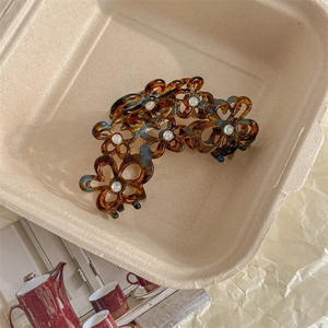 Dettaglio di un fermaglio per capelli a fiori con strass su carta vintage