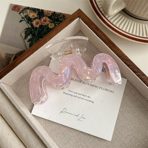 Détail d'une pince à cheveux rose nacrée ondulée dans un décor élégant et moderne
