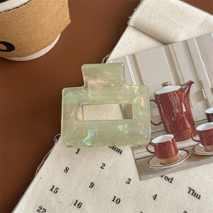 Macro detail of a light green iridescent hair claw clip with a hollow rectangular design