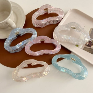 Lot de 6 pinces à cheveux irisées en forme de nuage aux tons pastel sur un bureau élégant