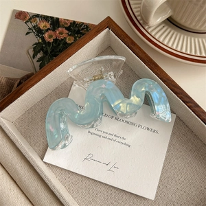 Détail d'une pince à cheveux ondulée en résine bleu clair aux reflets irisés