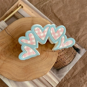 Detail of light blue heart-shaped hair claw with pink checkered patterns on wood