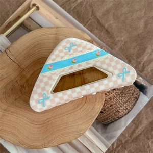 Detail of a large triangle hair claw clip featuring pink checkered peach and bow patterns