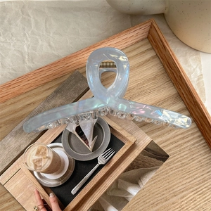 Detail of blue iridescent heart-shaped hair claw clip on a rustic wooden tray
