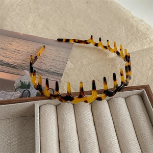 Macro detail of tortoiseshell wave headband with dual-layer teeth for volume styling