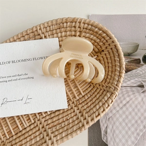 Detail of cream acetate hair claw featuring France Handmade gold lettering on rattan tray