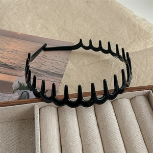 Close-up of black wavy headband with teeth on wooden jewelry box for daily hair styling