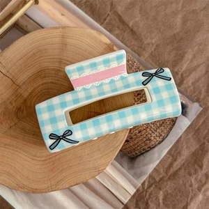 Detail of blue and white plaid hair claw with pink lace stripes and a blue bow accent