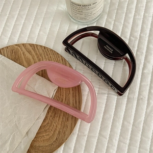 Minimalist geometric hair claws in pink and chocolate brown with gold label accents