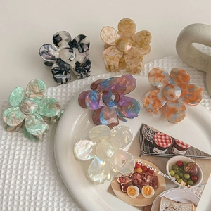 Elegant french acetate flower hair claws set in various colors on white porcelain plate
