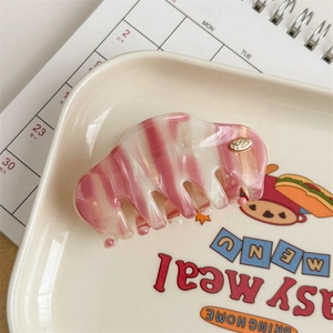 Detail view of pink and white striped acetate hair claw clip with golden YD logo insert