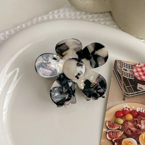 Detail of marble pattern acetate flower hair claw clip with golden handmade text logo