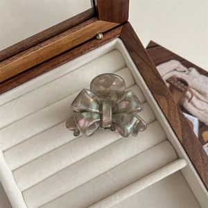 Macro detail of a smoke gray bow-shaped hair claw clip with pearlescent resin finish