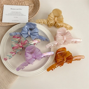 Large acetate bow hair claws in six colors displayed on a French decorative tray