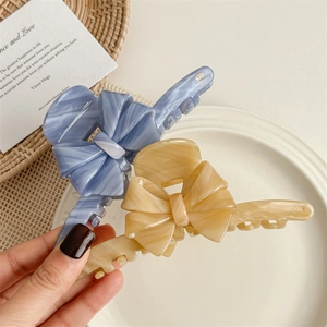Elegant acetate bow hair claws with marble texture in blue and beige tones
