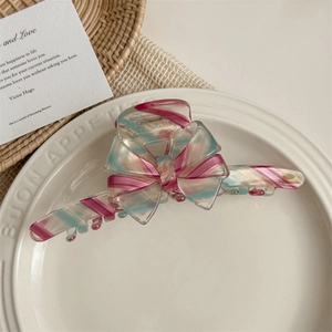 Close-up of pink and blue striped acetate bow hair claw with gold handmade logo detail