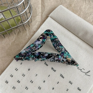Détail d'une grande pince à cheveux triangle en acétate avec un motif floral marbré élégant
