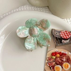 Detail of mint green marble acetate flower hair claw clip with golden handmade stamp
